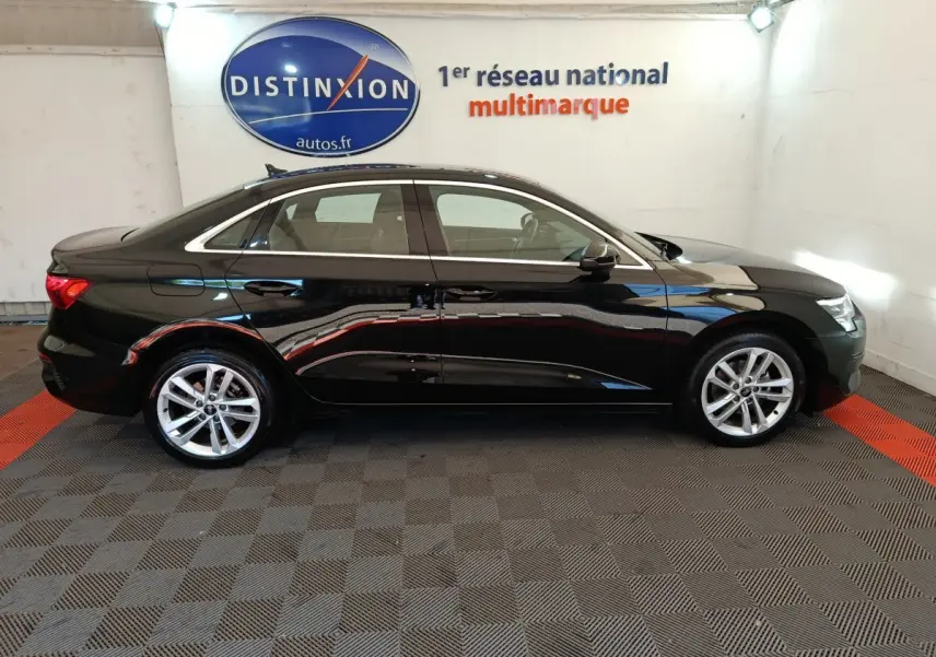 Profil côté gauche d'une Audi A3 noire 2022, berline élégante avec jantes alliage et lignes épurées en intérieur showroom.