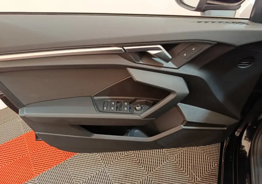 Vue rapprochée de la porte côté gauche noire de l'Audi A3 30 TFSI MHEV avec commandes de vitres et serrure intégrées.