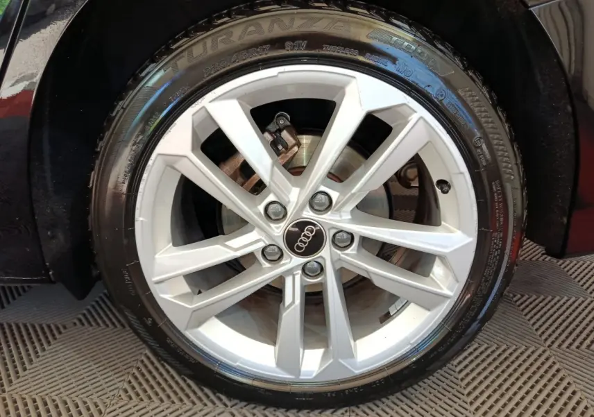 Gros plan sur la jante alliage argentée de l'Audi A3 noire, mettant en valeur le logo Audi au centre.