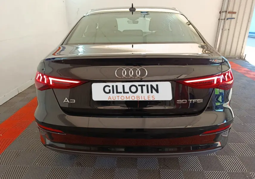Vue arrière d'une Audi A3 noire 30 TFSI avec feux LED allumés dans un garage éclairé.