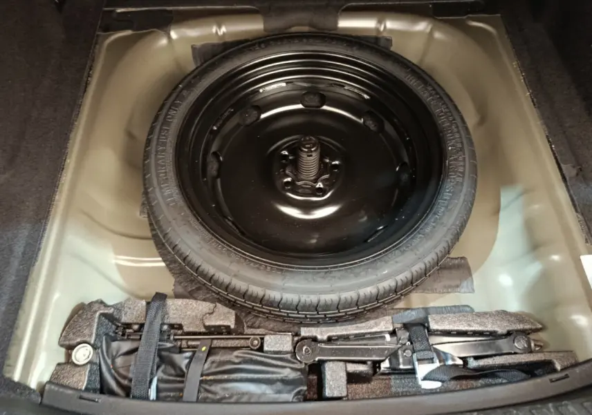 Vue plongeante sur la roue de secours noire et le kit de réparation dans le coffre d'une Audi A3 Business Line noire 2022.