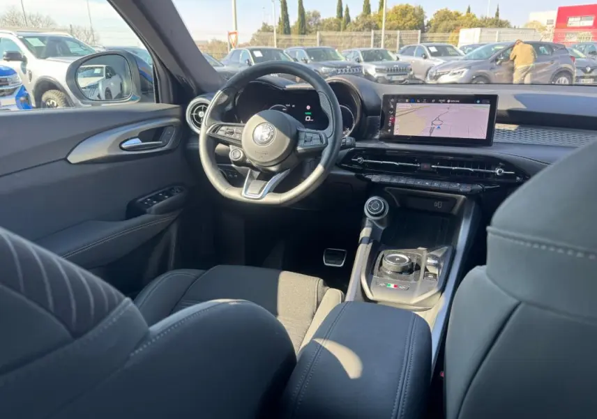 Vue intérieure avant de l'Alfa Romeo Tonale bleu foncé 2025, avec tableau de bord numérique et écran tactile central.