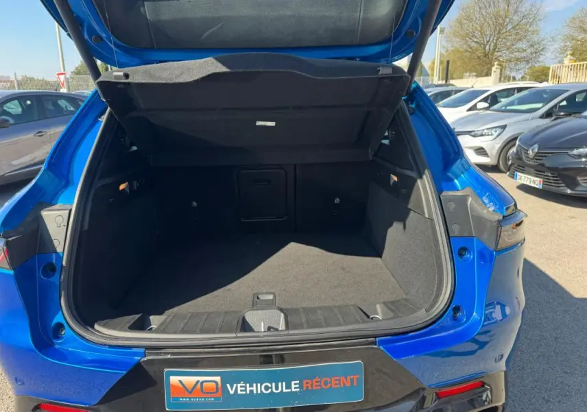 Coffre ouvert vu de l’arrière d’une Alfa Romeo Tonale bleu foncé, avec hayon relevé et intérieur spacieux visible.