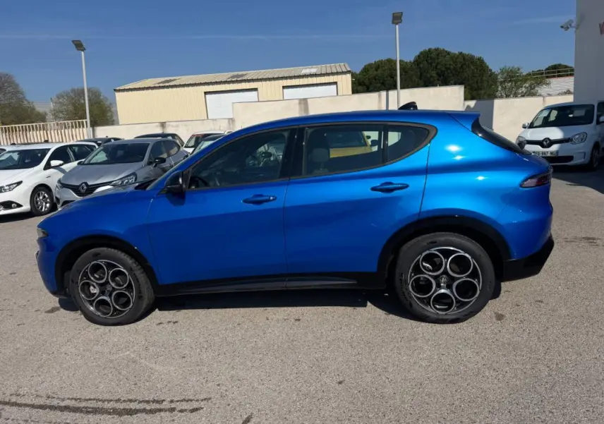 Vue de profil côté gauche d'un Alfa Romeo Tonale bleu foncé 2025 avec jantes distinctives à cinq cercles.