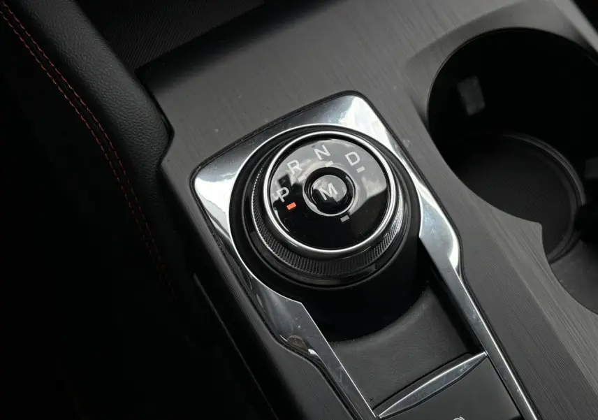 Gros plan sur le sélecteur rotatif de boîte automatique dans l’habitacle noir du Ford Kuga bleu azur 2023 finition ST-Line X.