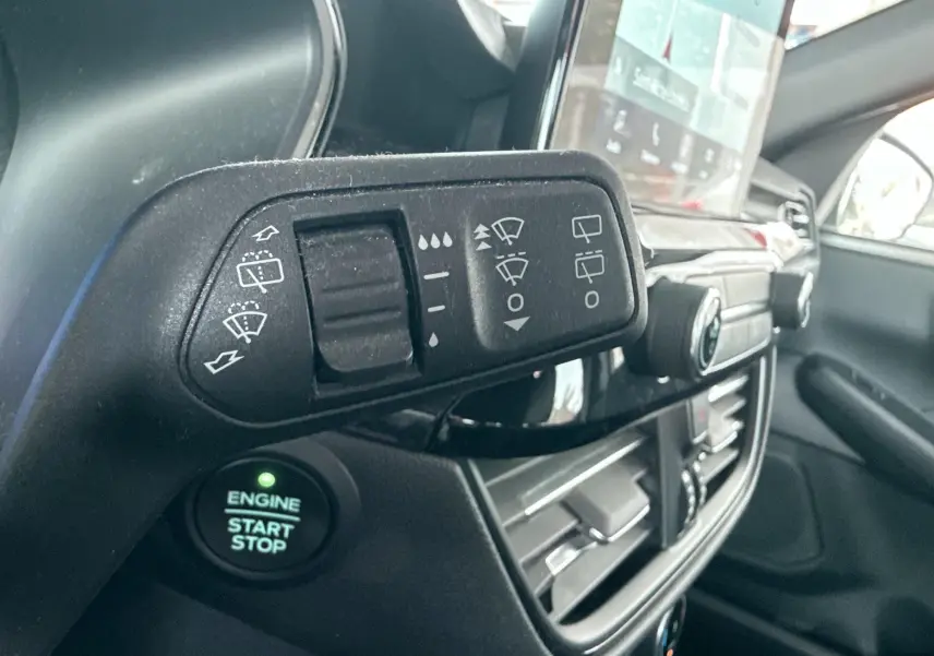 Gros plan sur la commande d’essuie-glace et bouton start/stop dans l’habitacle du Ford Kuga bleu azur 2023.