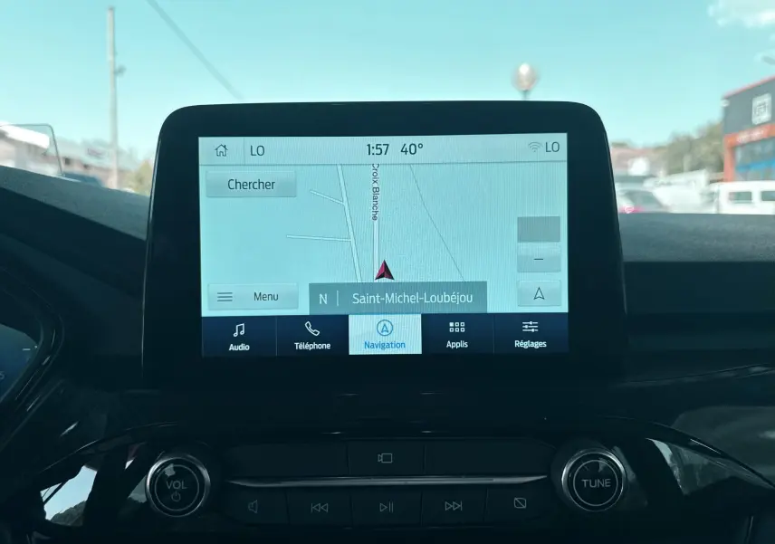 Écran tactile central du Ford Kuga bleu azur 2023 affichant la navigation avec commandes audio et téléphone visibles.