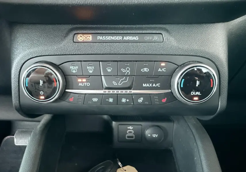 Vue rapprochée du tableau de bord du Ford Kuga 2023, montrant la console de climatisation avec commandes digitales et ports USB.