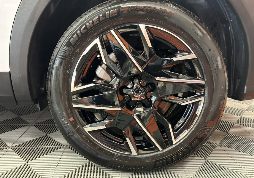 Gros plan sur la roue avant droite d’un Peugeot 5008 blanc, jante alliage noire et argentée avec pneu Michelin.