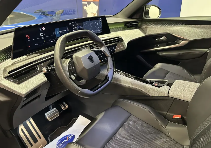 Vue intérieure côté conducteur du Peugeot 5008 Hybrid 2025, avec tableau de bord numérique large et volant compact noir.