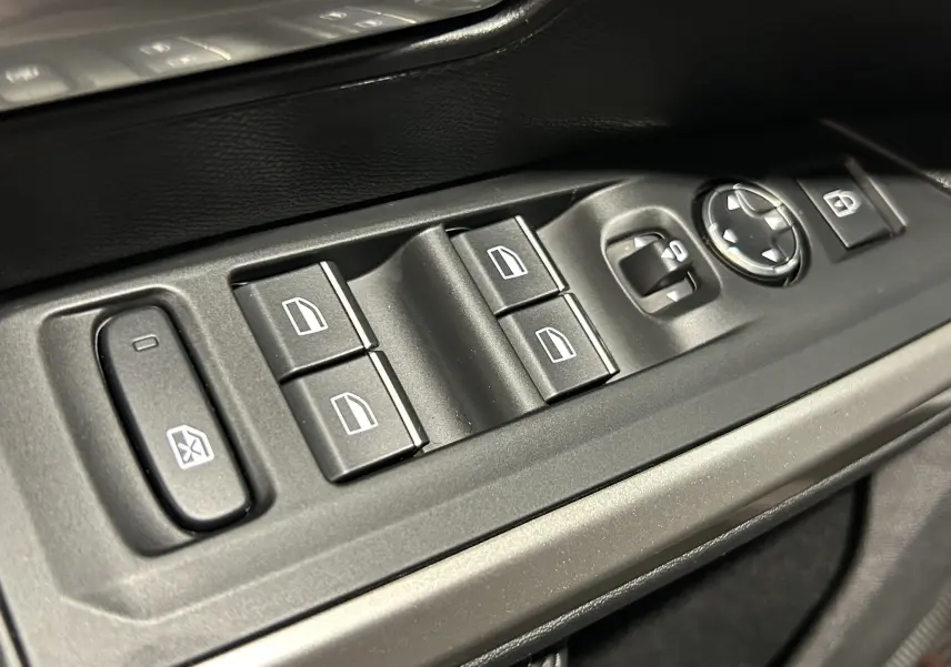 Gros plan sur les commandes de lève-vitres et réglages des rétroviseurs côté conducteur d’un Peugeot 5008 blanc.