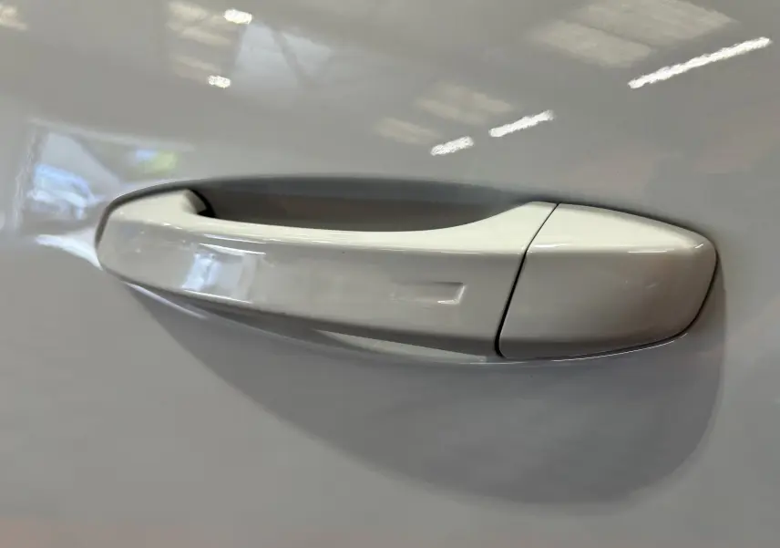 Poignée de porte blanche en gros plan sur le côté gauche d’un Peugeot 5008 Hybrid 2025.