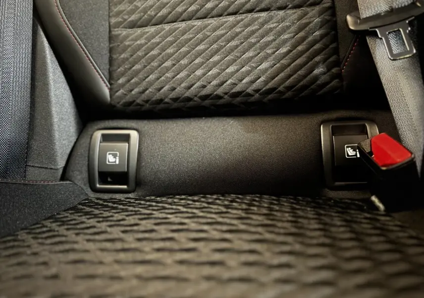 Gros plan sur les fixations Isofix arrière et la ceinture de sécurité rouge dans l’habitacle noir de la Renault Clio gris clair.