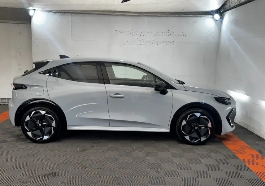 Profil droit de la Renault Clio Techno TCe 115 gris clair 2026 avec jantes noires et rétroviseurs rabattables électriques.