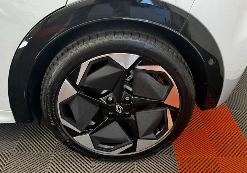 Gros plan sur la roue avant droite d’une Renault Clio gris clair, jante noire et argentée au design géométrique.
