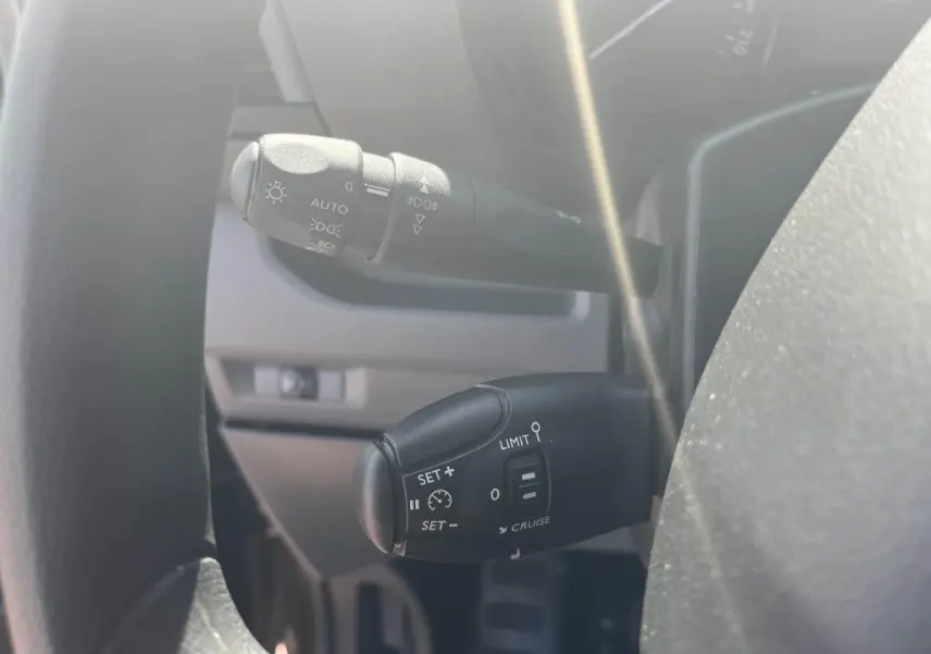Gros plan sur les commandes de régulateur et feux automatiques du Peugeot Expert Fourgon gris platinium 2023.