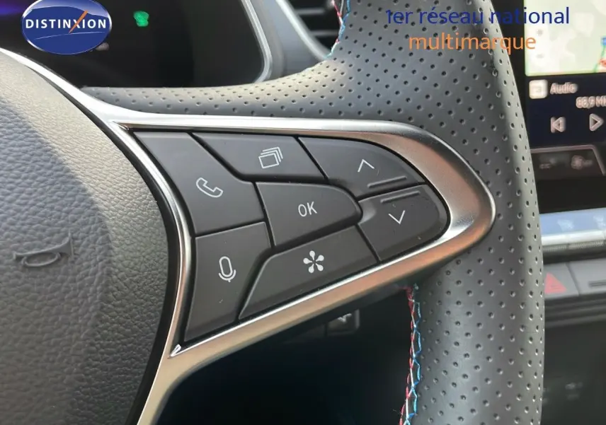 Gros plan sur les commandes multifonctions du volant en cuir perforé noir avec surpiqûres tricolores du Renault Captur E-Tech hybride 2025.