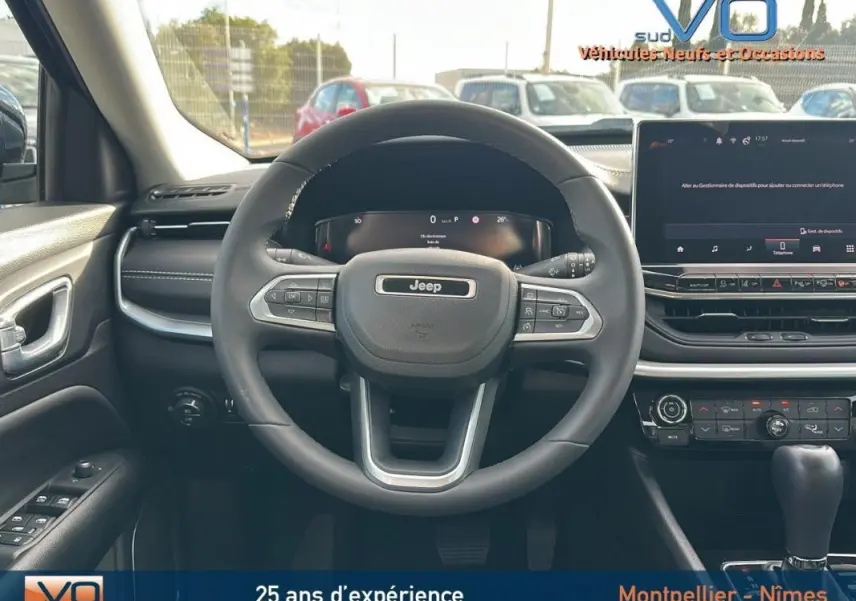 Vue centrée sur le volant et tableau de bord du Jeep Compass gris 2024 avec écran tactile et commandes au volant.