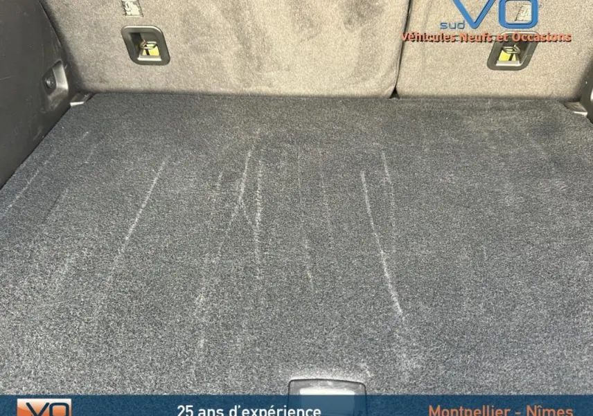 Coffre spacieux du Jeep Compass gris 2024 vu de l'intérieur, avec tapis de sol et sièges arrière rabattus.