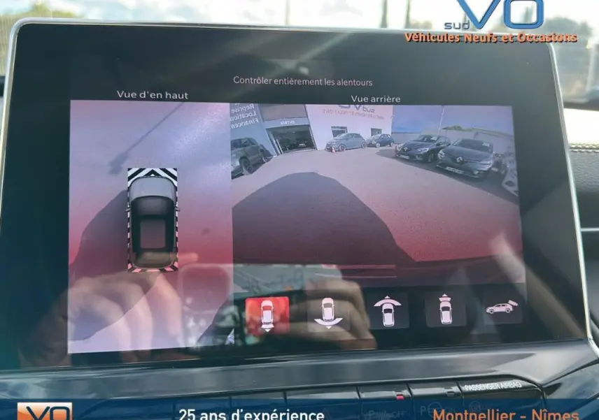 Écran tactile montrant la caméra de recul et vue en hauteur du Jeep Compass gris 2024 en stationnement.