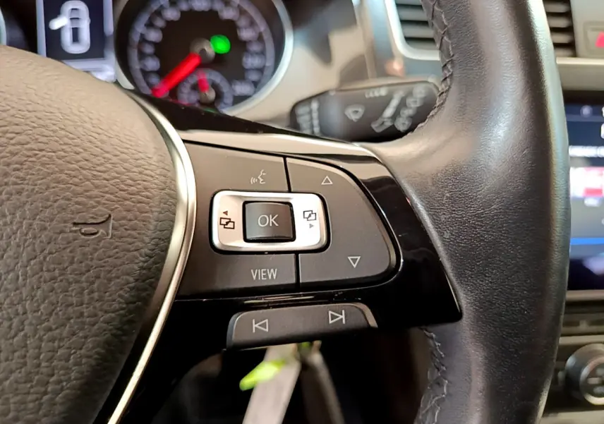 Gros plan sur les commandes du volant cuir de la Volkswagen Golf 2019, avec tableau de bord et écran tactile en arrière-plan.