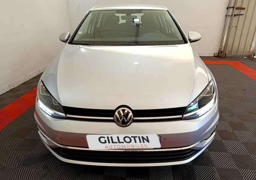 Vue frontale d'une Volkswagen Golf gris clair 2019 avec phares LED et calandre noire brillante.