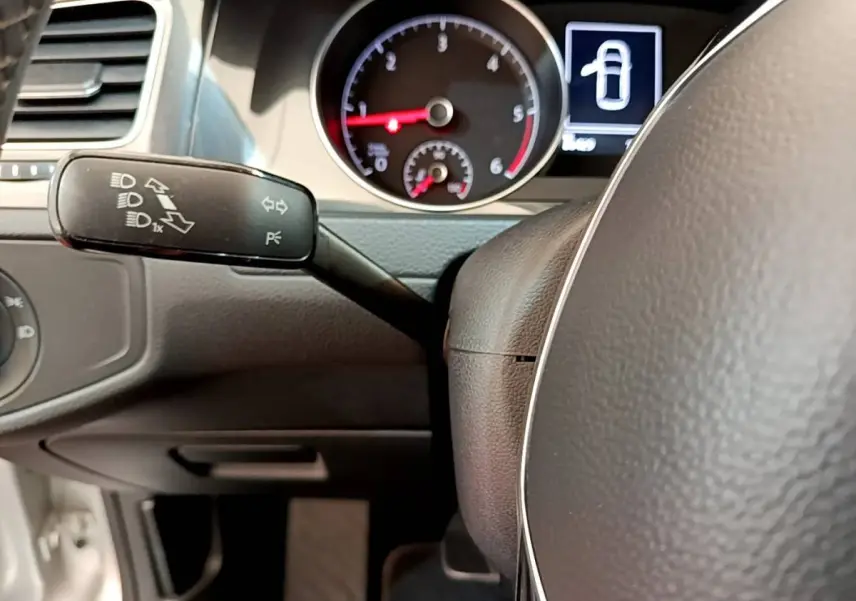 Gros plan sur le volant et le commodo gauche du tableau de bord d'une Volkswagen Golf gris clair de 2019.