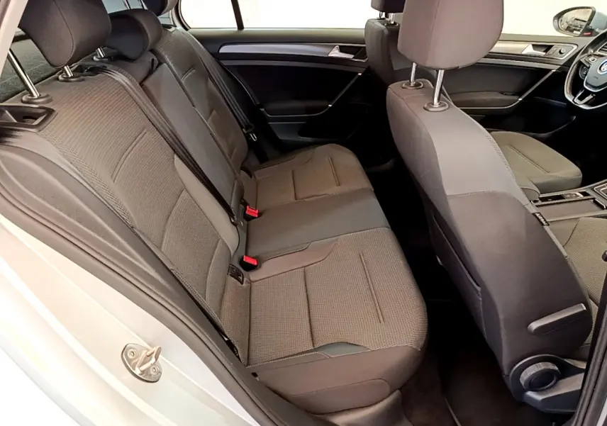 Vue intérieure côté gauche arrière de la Volkswagen Golf gris clair 2019, sièges tissu gris et tableau de bord visible.