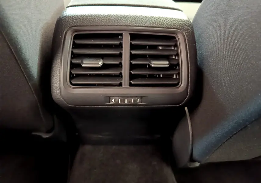 Grille d'aération arrière noire vue de face entre les sièges avant d'une Volkswagen Golf 2019 gris clair.