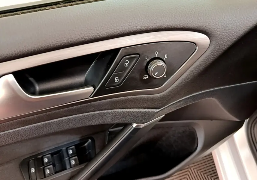Gros plan sur la porte côté conducteur de la Volkswagen Golf gris clair, montrant les commandes des rétroviseurs et des vitres électriques.