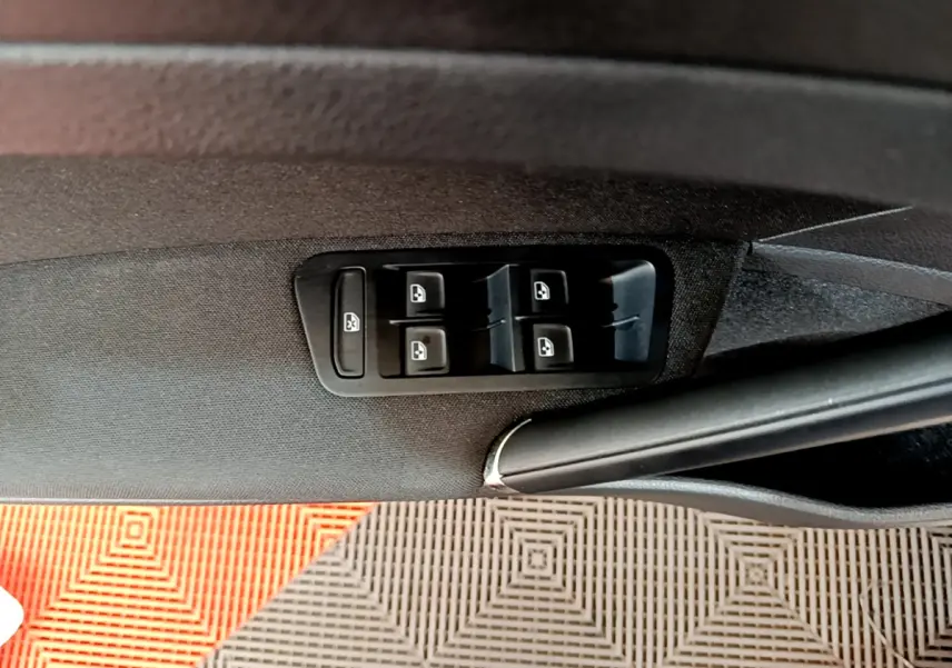 Gros plan sur les commandes des vitres électriques côté conducteur d'une Volkswagen Golf gris clair de 2019.