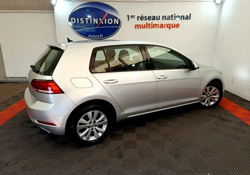 Vue côté droit arrière d'une Volkswagen Golf gris clair 2019 garée en intérieur avec jantes alliage et feux arrière LED.