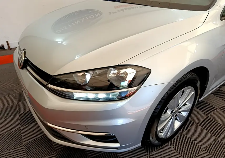 Vue 3/4 avant droit d'une Volkswagen Golf gris clair avec phares LED et jantes alliage visibles.