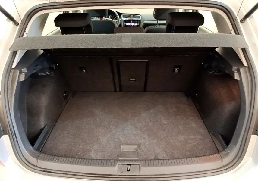 Coffre ouvert d'une Volkswagen Golf gris clair 2019, vue arrière montrant l'espace de chargement et la banquette arrière.