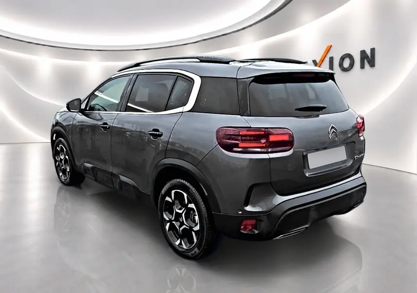 Citroën C5 Aircross gris vue 3/4 arrière droit, avec barres de toit et jantes alliage distinctives.