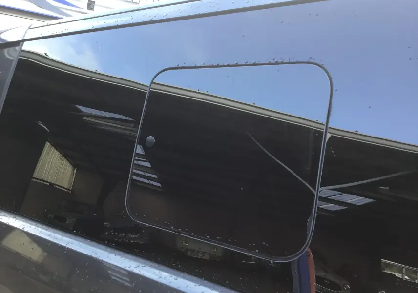 Reflet de la vitre coulissante côté droit du Volkswagen Transporter ProCab gris anthracite 2025 sous lumière naturelle