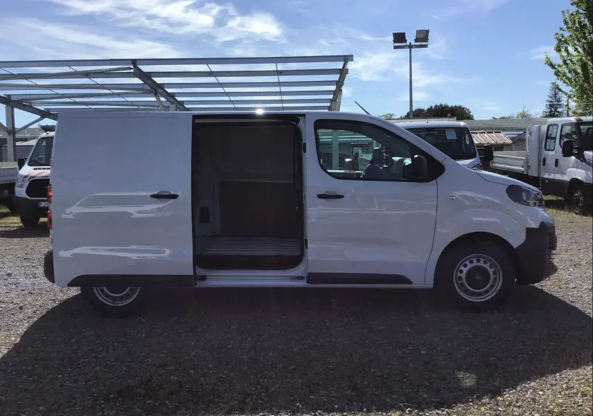 Profil côté droit du Peugeot Expert Fourgon blanc 2025 avec porte coulissante ouverte montrant l'espace de chargement vide.