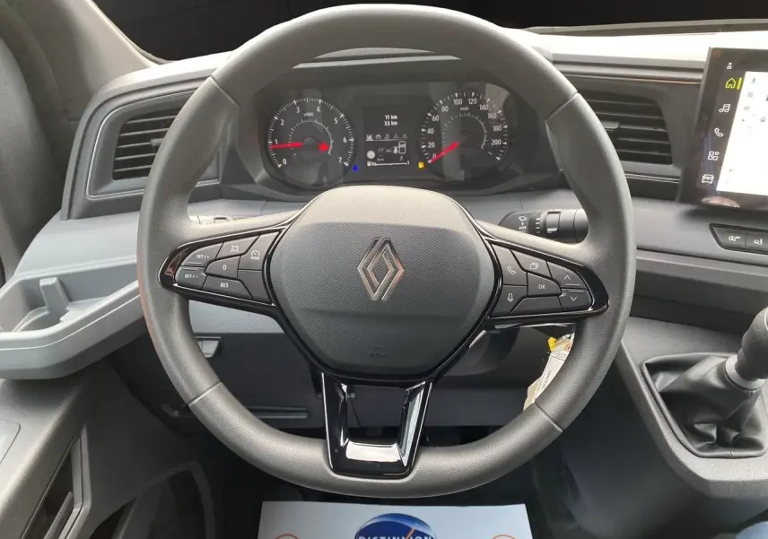 Vue rapprochée du volant et du tableau de bord du Renault Master 2025 avec commandes intégrées et levier de vitesses manuel.