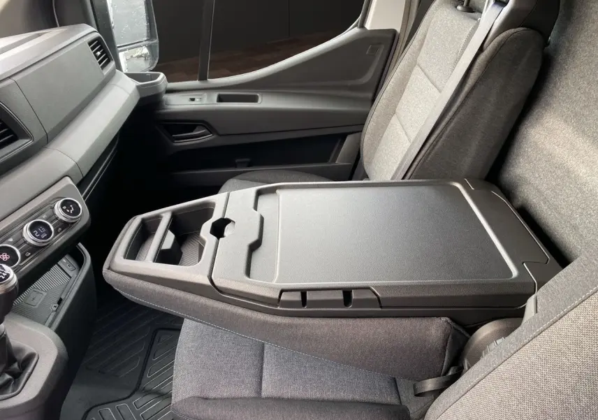 Vue intérieure côté passager du Renault Master blanc 2025, mettant en valeur la banquette avec bureau mobile intégré.
