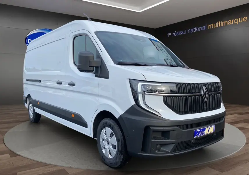 Vue 3/4 avant d’un Renault Master blanc avec calandre noire et enjoliveurs argentés, stationné en intérieur.