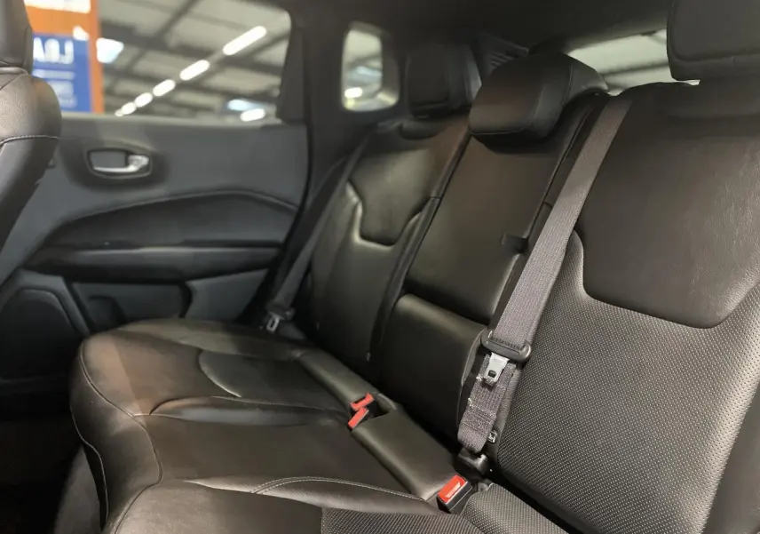 Vue latérale intérieure des sièges arrière en cuir noir du Jeep Compass Trailhawk 2021 avec ceinture de sécurité grise.