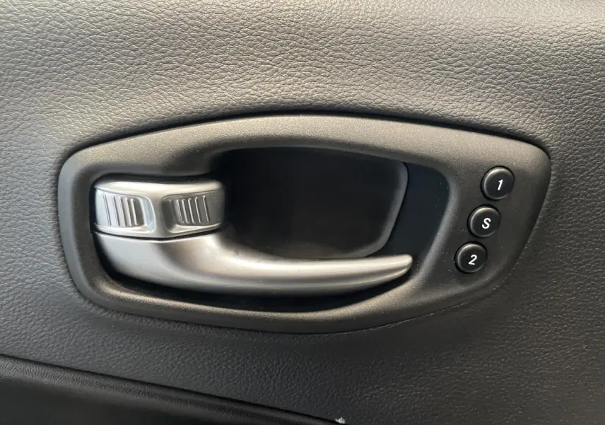 Poignée intérieure de porte noire avec commandes de réglage mémoire des sièges sur Jeep Compass Trailhawk gris foncé.