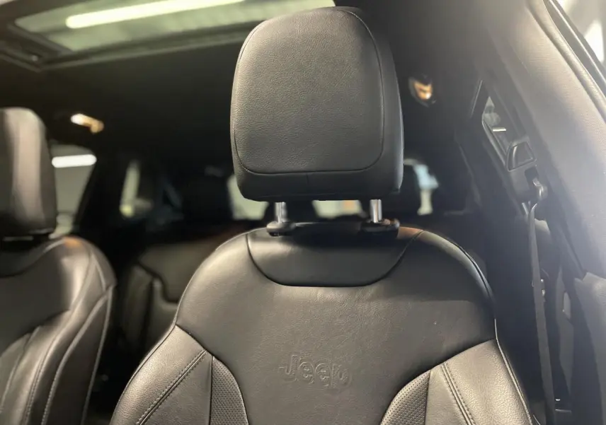 Gros plan sur le siège avant en cuir noir embossé Jeep, avec toit ouvrant panoramique visible en arrière-plan.