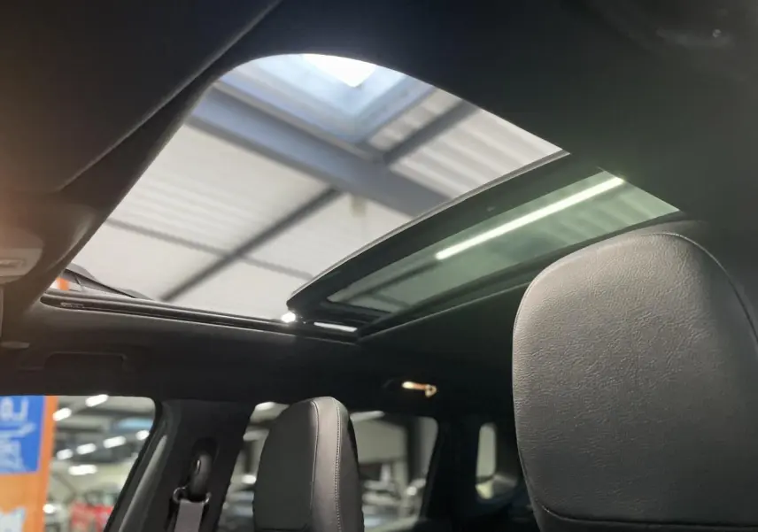 Toit ouvrant panoramique ouvert sur l'intérieur noir cuir du Jeep Compass Trailhawk 2021 en gris foncé.