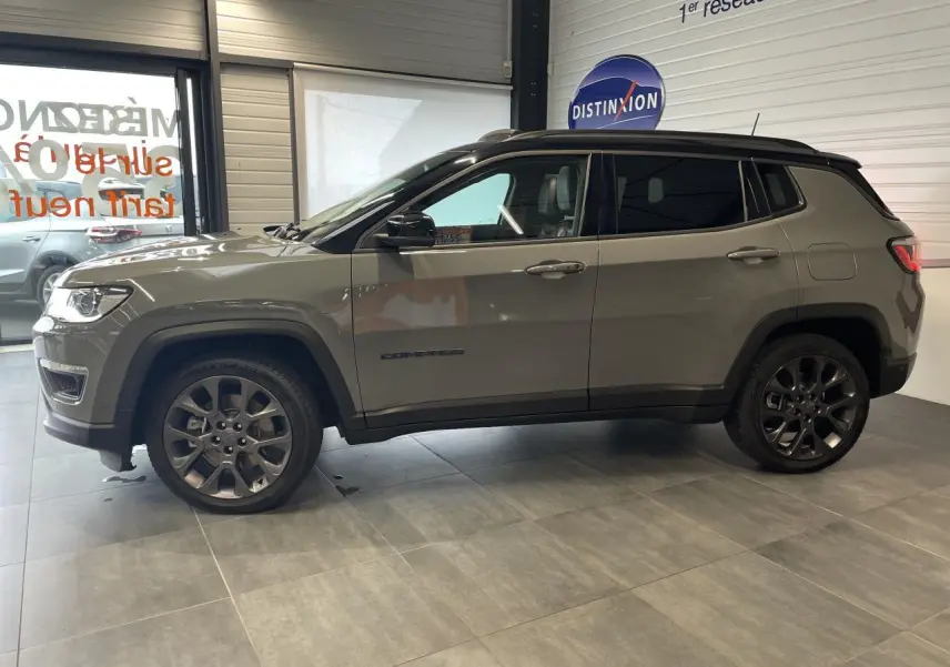 Jeep Compass gris foncé vu de profil côté gauche, avec jantes alliage foncé et vitres arrière surteintées.