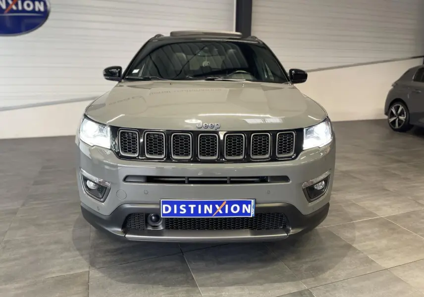Jeep Compass gris foncé vue de face en intérieur, avec calandre à sept fentes et phares LED allumés.