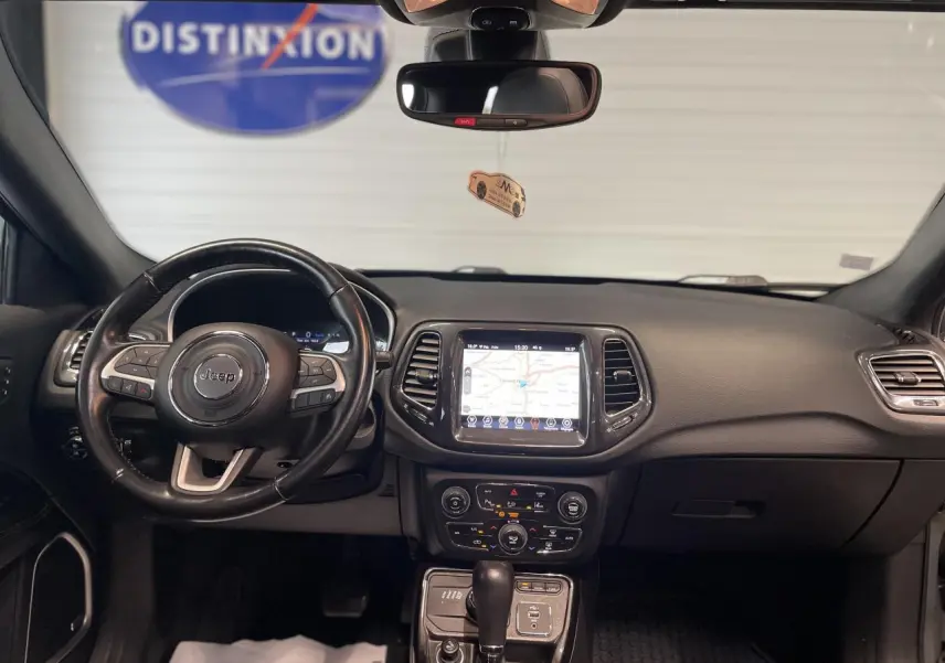Vue intérieure frontale du tableau de bord noir du Jeep Compass 2021 avec écran tactile GPS et volant cuir.