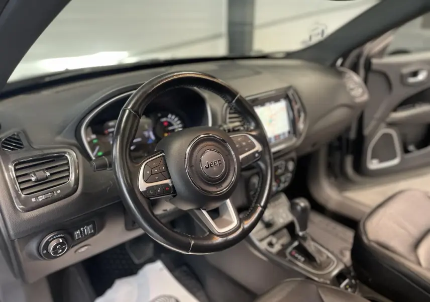 Intérieur du Jeep Compass 2021, vue côté conducteur sur le volant cuir et tableau de bord avec écran tactile.