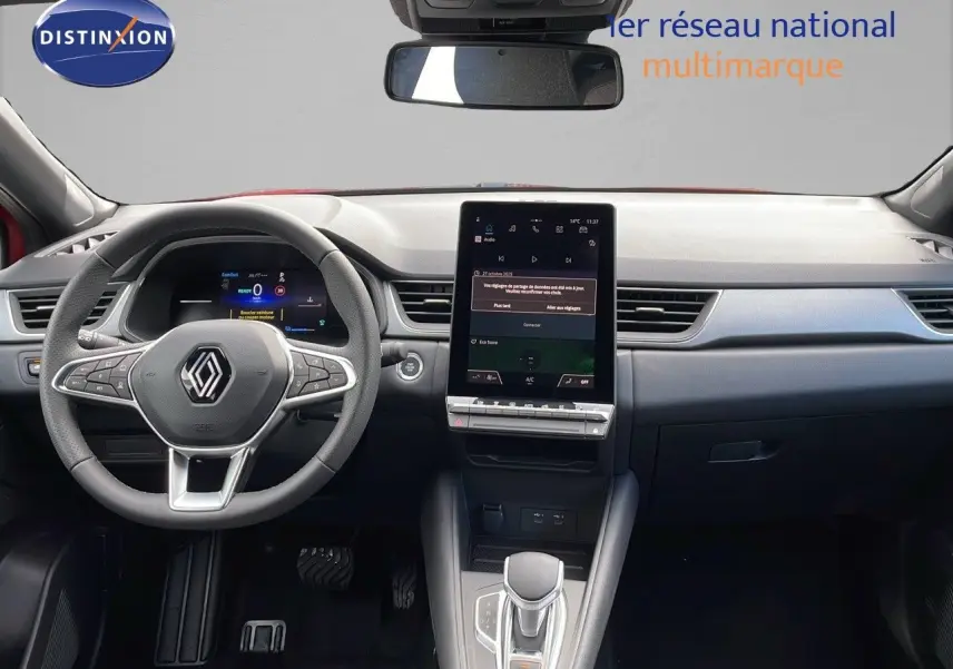 Intérieur avant du Renault Captur E-Tech hybride 2025, tableau de bord moderne avec écran tactile vertical et volant multifonction.