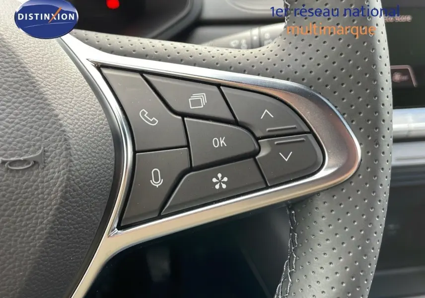 Gros plan sur les commandes multifonctions à droite du volant perforé d'un Renault Captur rouge passion 2025.